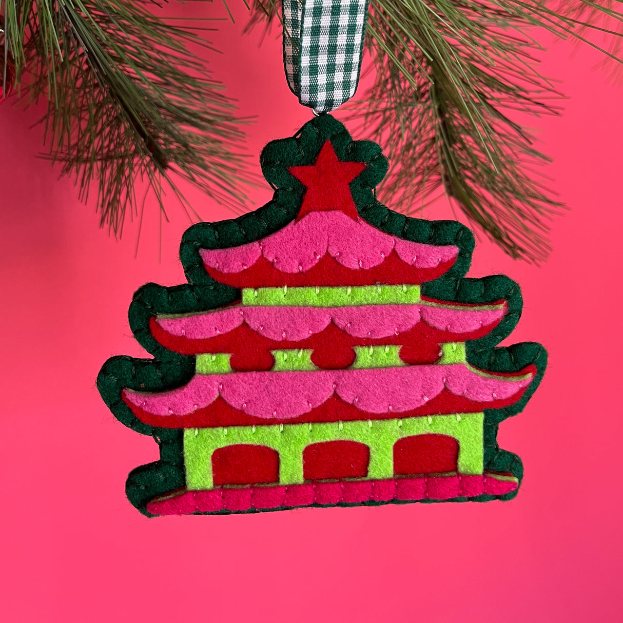 pink felt chinoiserie christmas ornaments in the shape of pagodas against a red background 