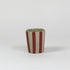 A striped ceramic cup in red striped on a white background. 