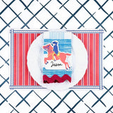 A styled patriotic table setting featuring a red white and blue striped paper placemat, white plate, striped napkin, and decorative place card.
