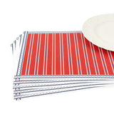 A stacked set of patriotic paper placemats featuring red white and blue striped patterns beside a white plate.