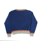 Back view of blue knit cardigan with contrast trim at the collar, cuffs, and hem on a white background