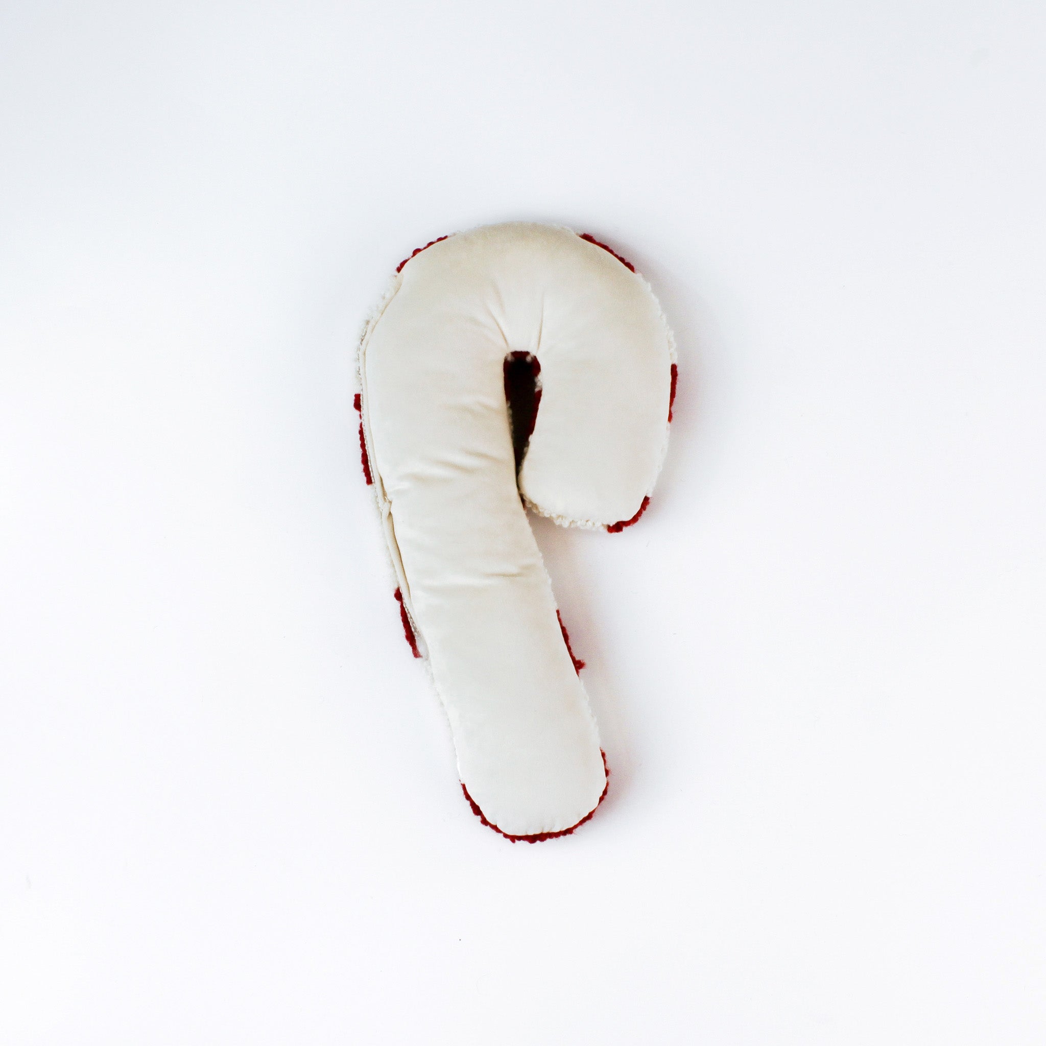 back of the candy cane–shaped decorative pillow with red and white stripes, made from a textured hooked fabric and displayed against a white background.