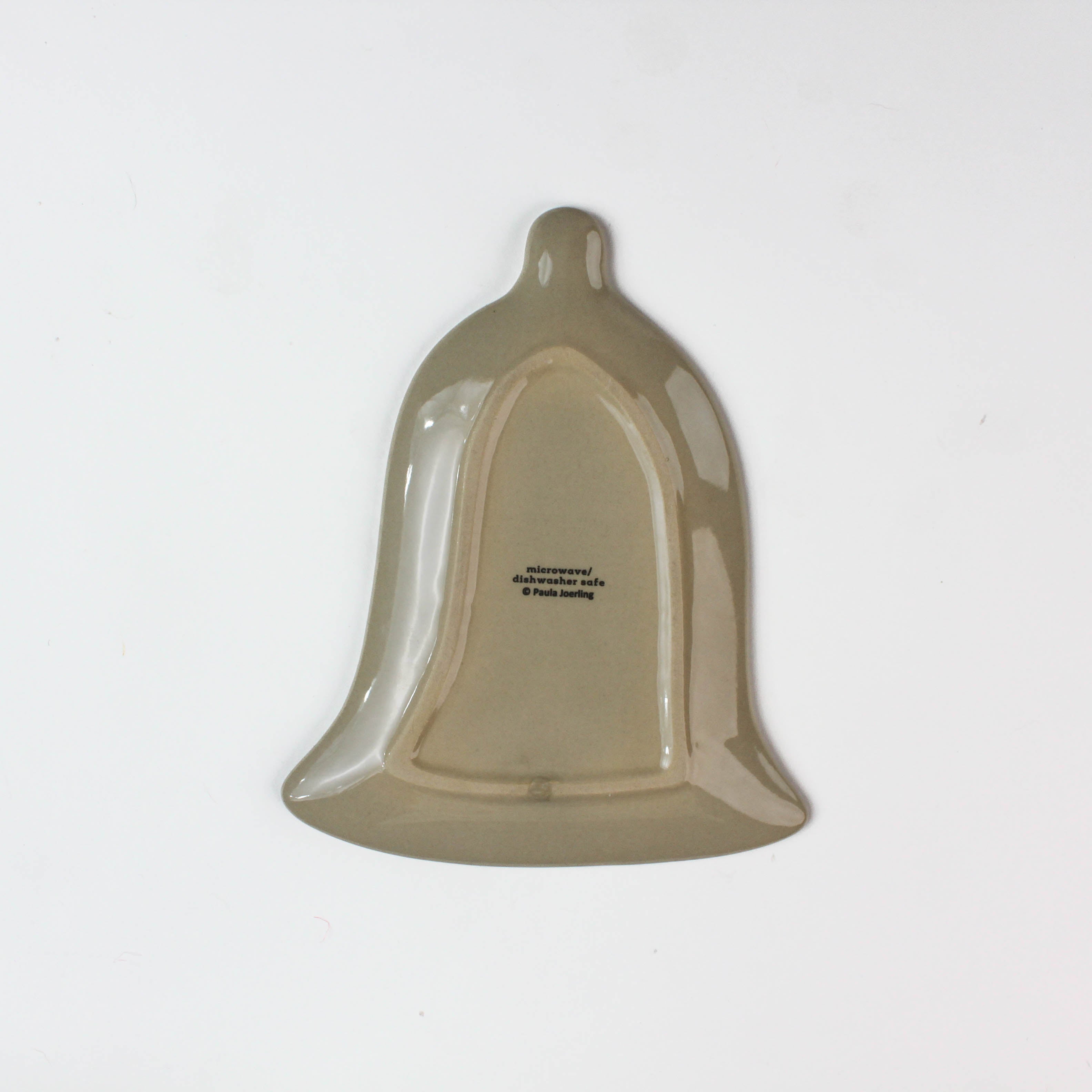 reverse side of a bell shaped christmas accent plate on a white background