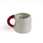 reverse side of a ceramic Christmas santa mug with a jolly santa face design with red cheeks and a red handle on a white background