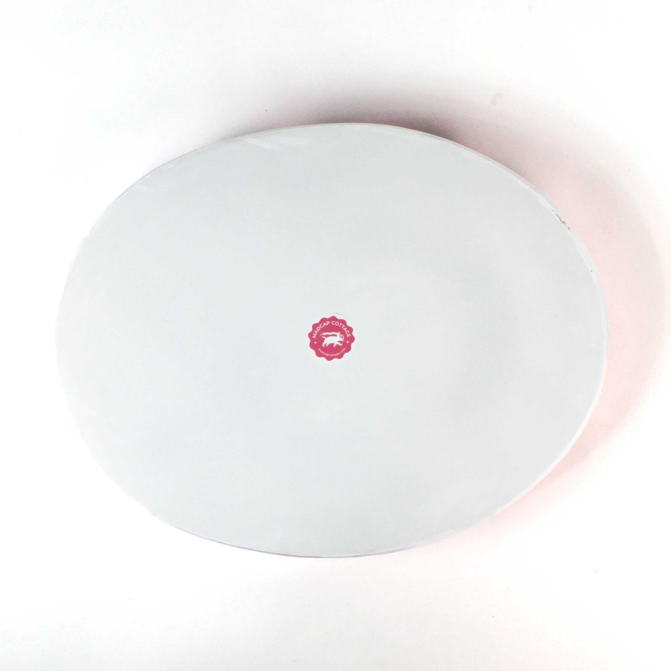 bottom view of the Hand-Painted Metal Christmas Santa Tray featuring a cheerful Santa Claus face with a red hat on a pink circular background with scalloped edges.