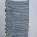 the reverse side of A rectangular blue accent rug with small daisy shaped accents scattered across it. 