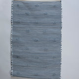the reverse side of A rectangular blue accent rug with small daisy shaped accents scattered across it. 