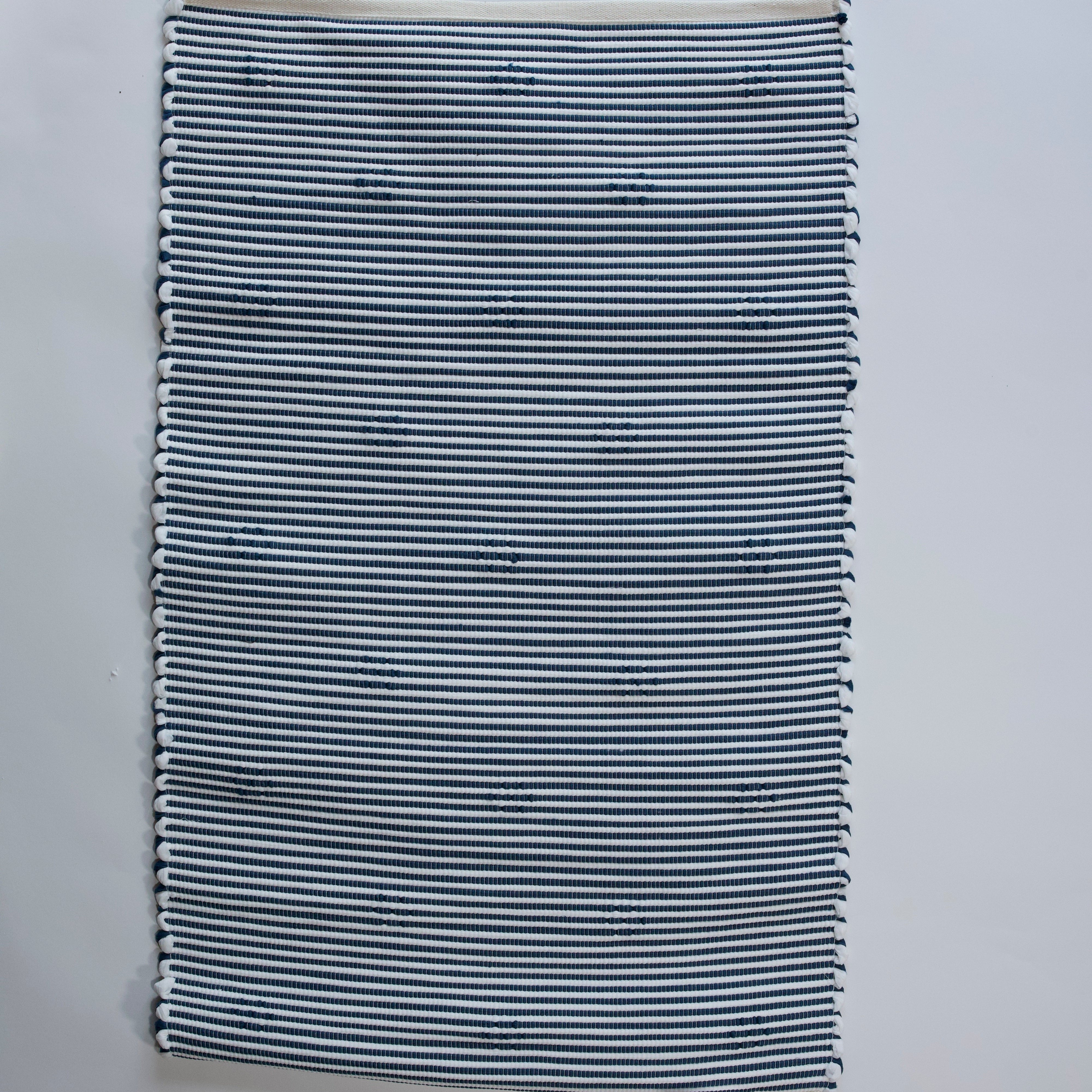 the reverse side of A rectangular blue accent rug with small daisy shaped accents scattered across it. 