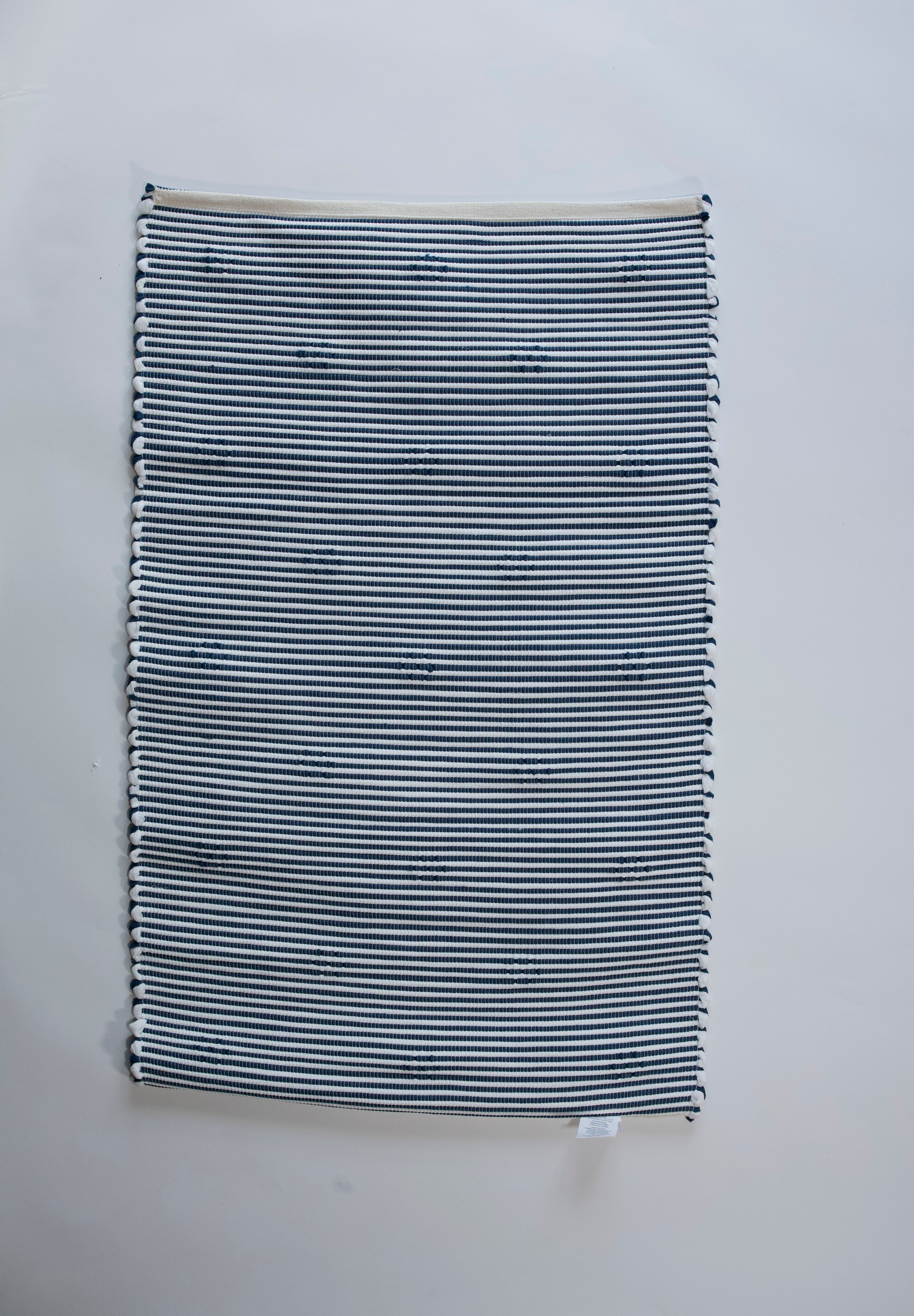 the reverse side of A rectangular blue accent rug with small daisy shaped accents scattered across it. 