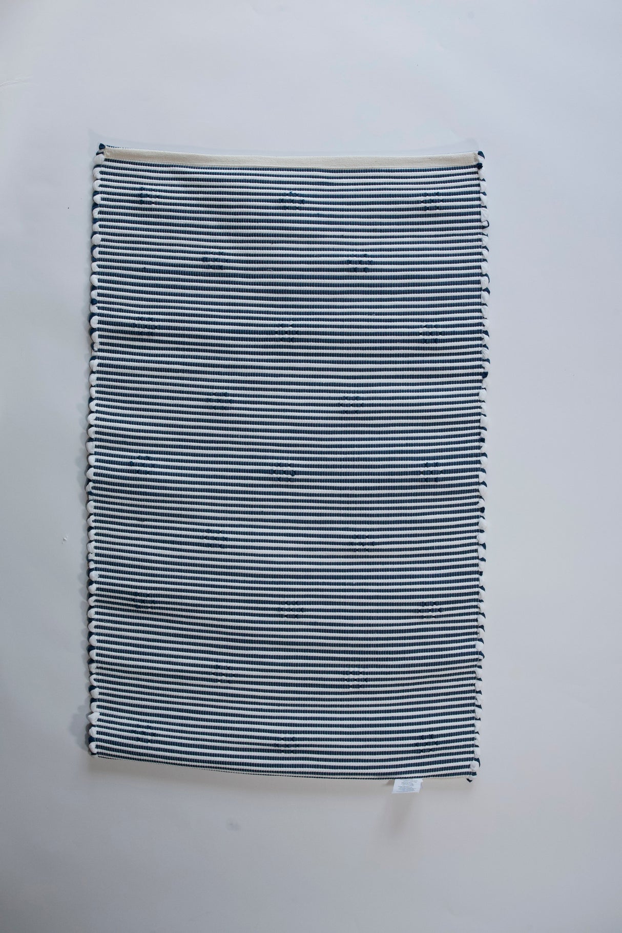the reverse side of A rectangular blue accent rug with small daisy shaped accents scattered across it. 