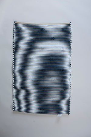 the reverse side of A rectangular blue accent rug with small daisy shaped accents scattered across it. 