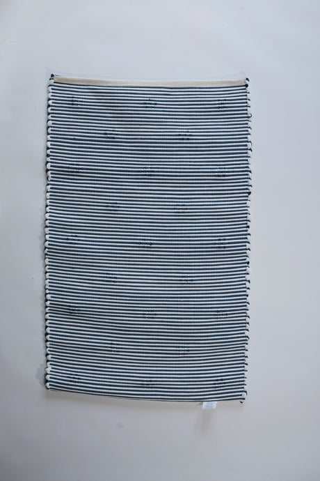 the reverse side of A rectangular blue accent rug with small daisy shaped accents scattered across it. 