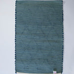 reverse side of A madcap cottage navy  accent rug with a lattice motif across the front