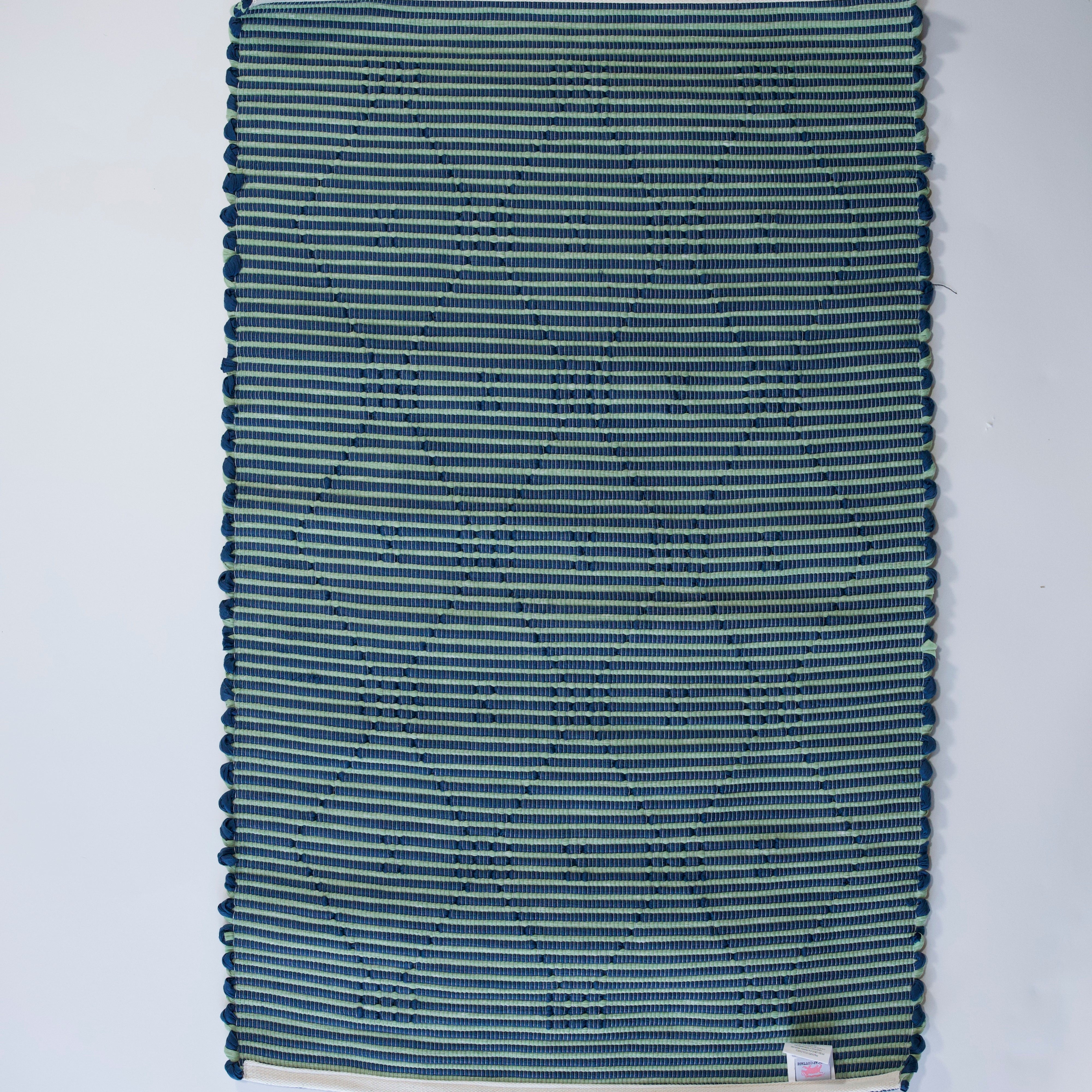 reverse side of A madcap cottage navy  accent rug with a lattice motif across the front