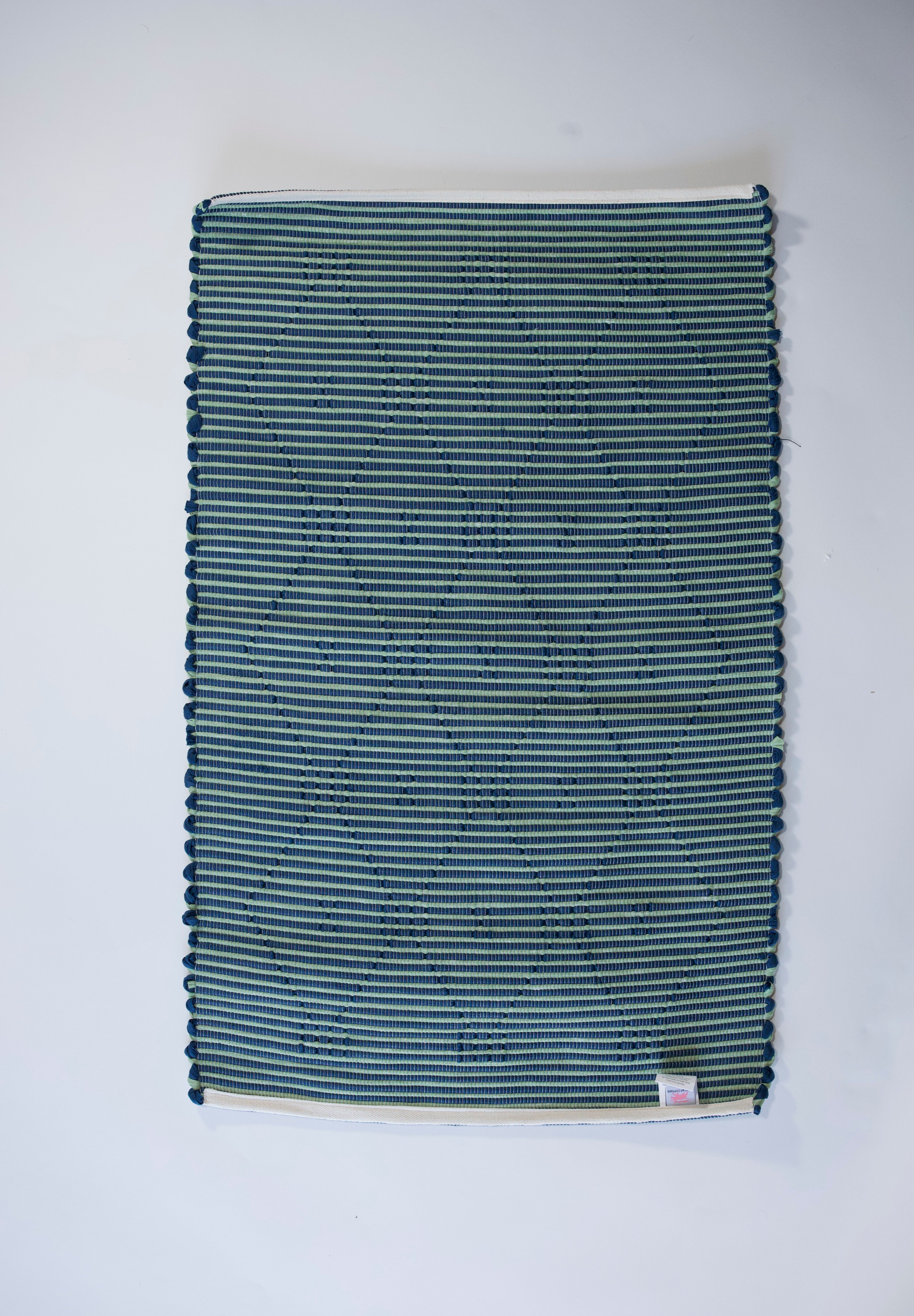 reverse side of A madcap cottage navy  accent rug with a lattice motif across the front