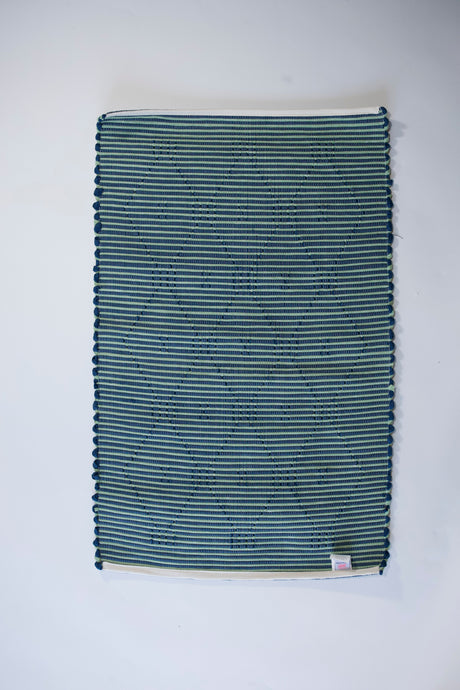 reverse side of A madcap cottage navy  accent rug with a lattice motif across the front
