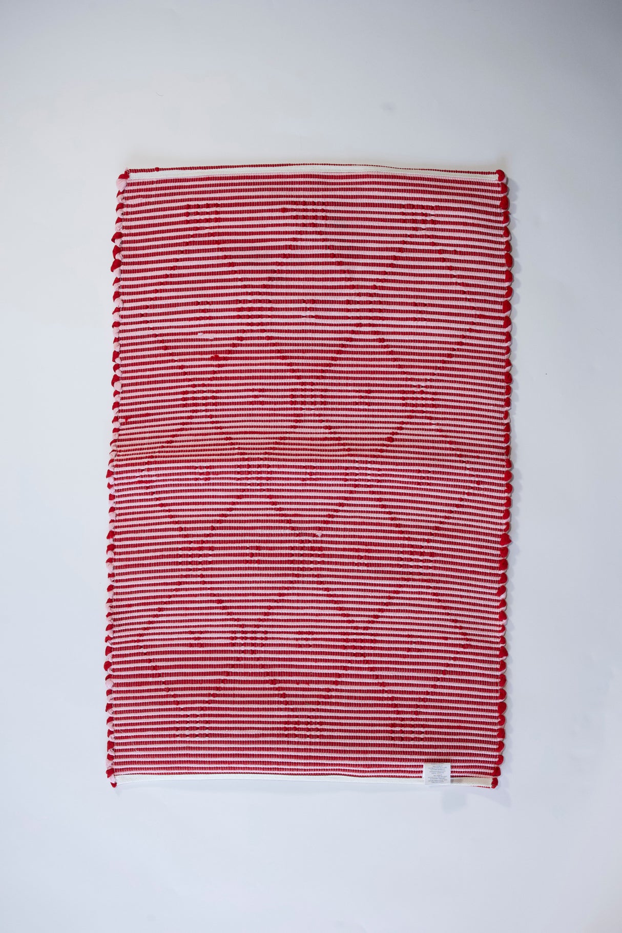 the reverse side of A madcap cottage yellow and green striped accent rug with a lattice motif across the front