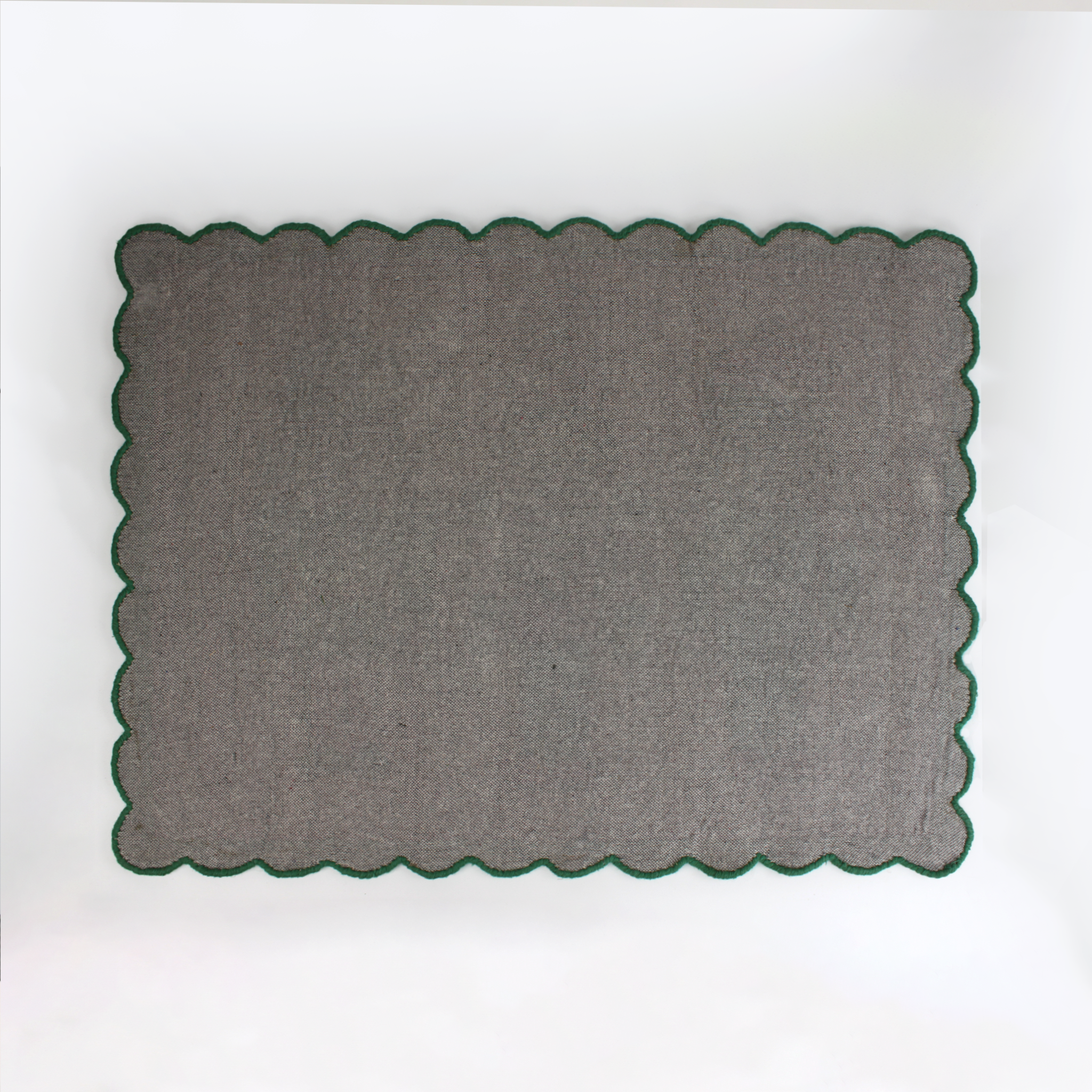 reverse of a PInk and green christmas rug featuring three nutcrackers and a green scalloped border