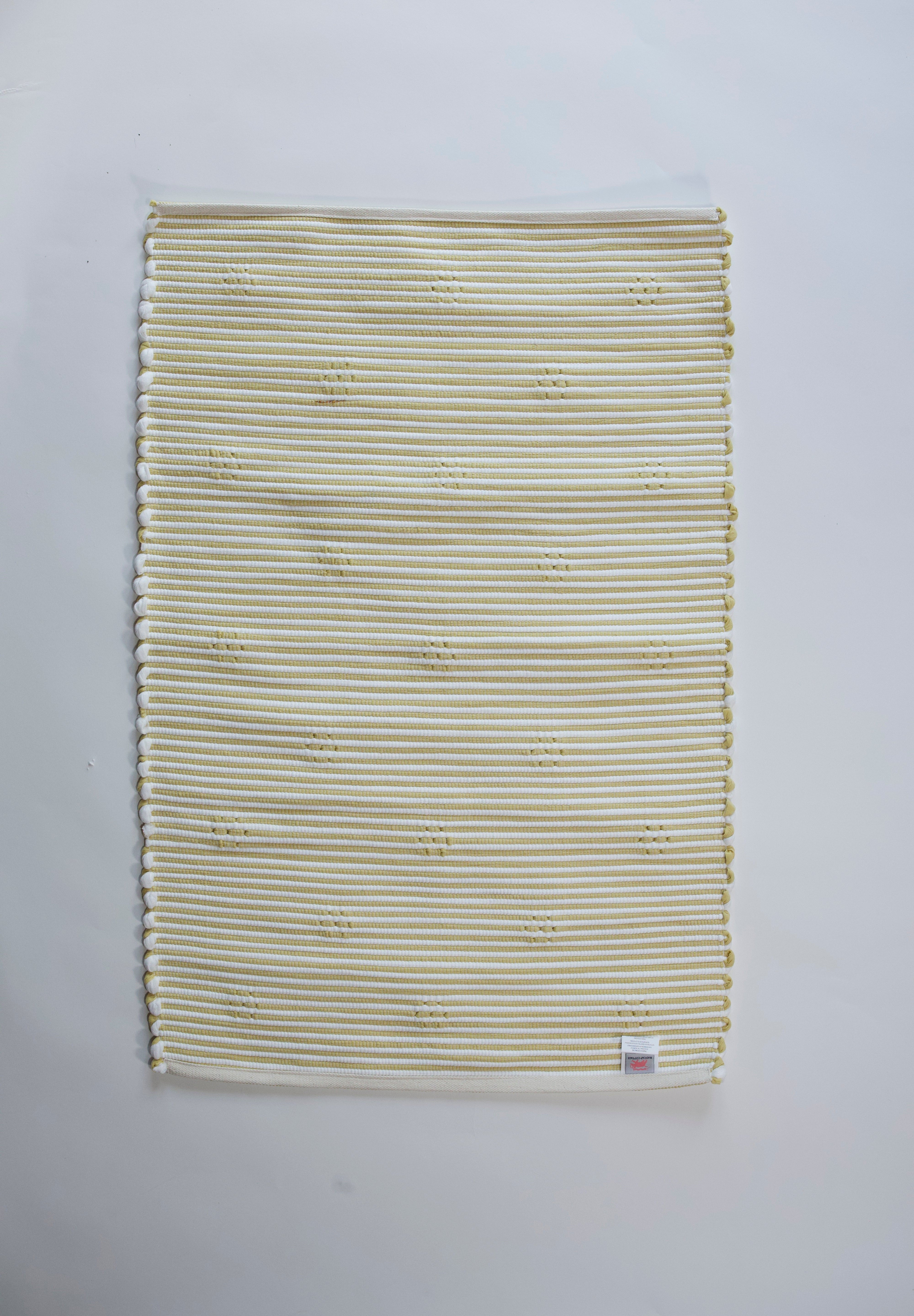 reverse side of a rectangular yellow accent rug with small daisy shaped accents scattered across it. 