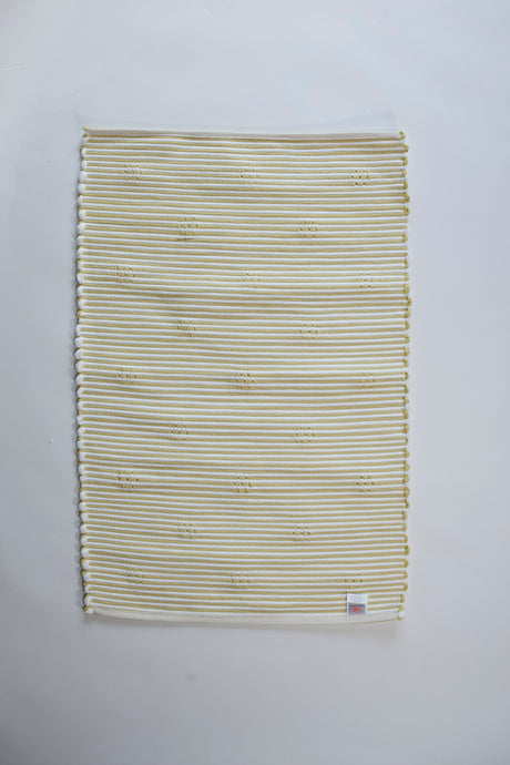 reverse side of a rectangular yellow accent rug with small daisy shaped accents scattered across it. 
