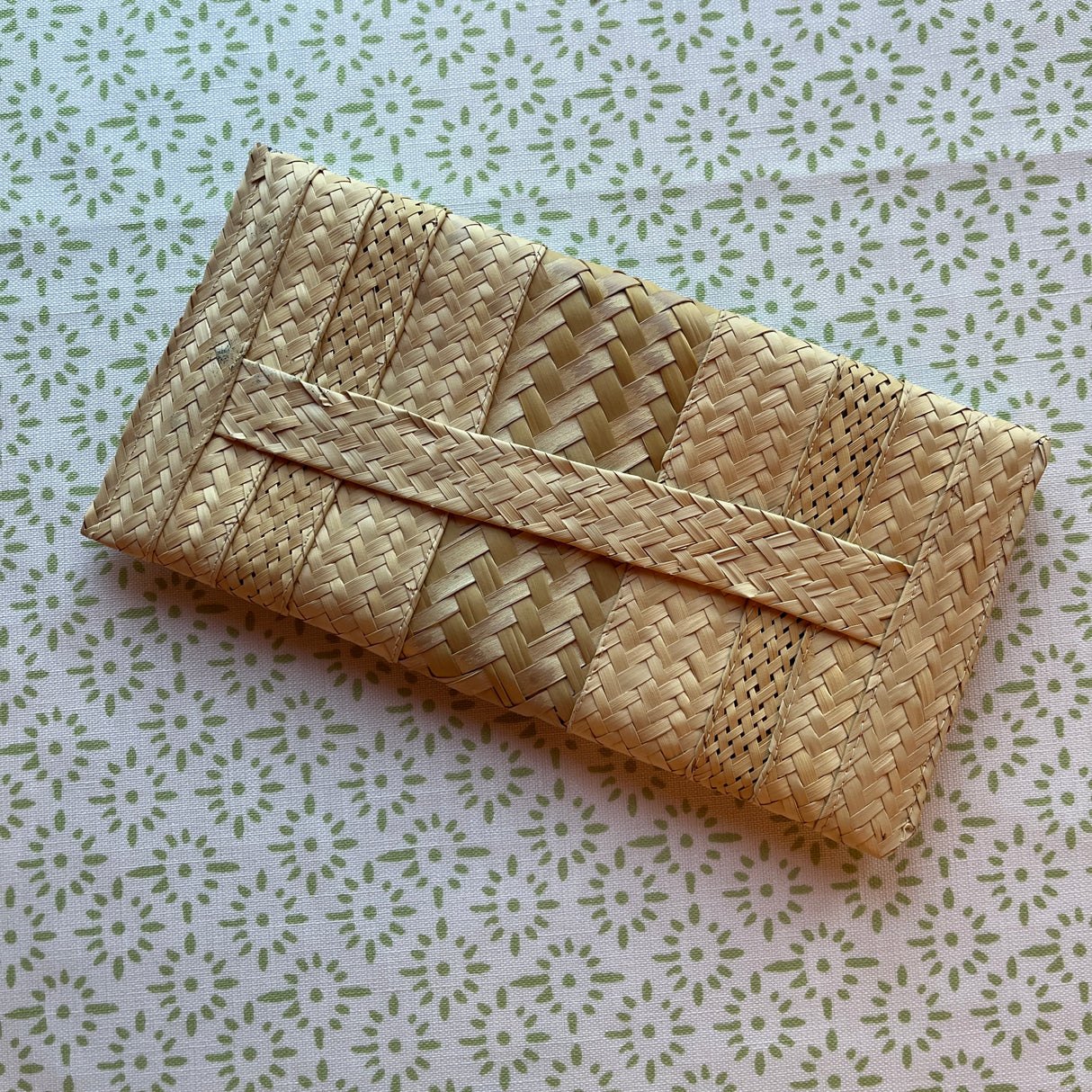 reverse side of a vintage straw clutch bag with yellow and red flowers around the front