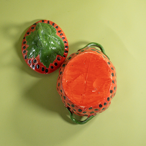 a large red vintage strawberry dish with a green handles and green detail on lid