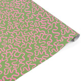 Playful gift wrap featuring whimsical pink ribbon patterns on a vibrant green background for gifting.