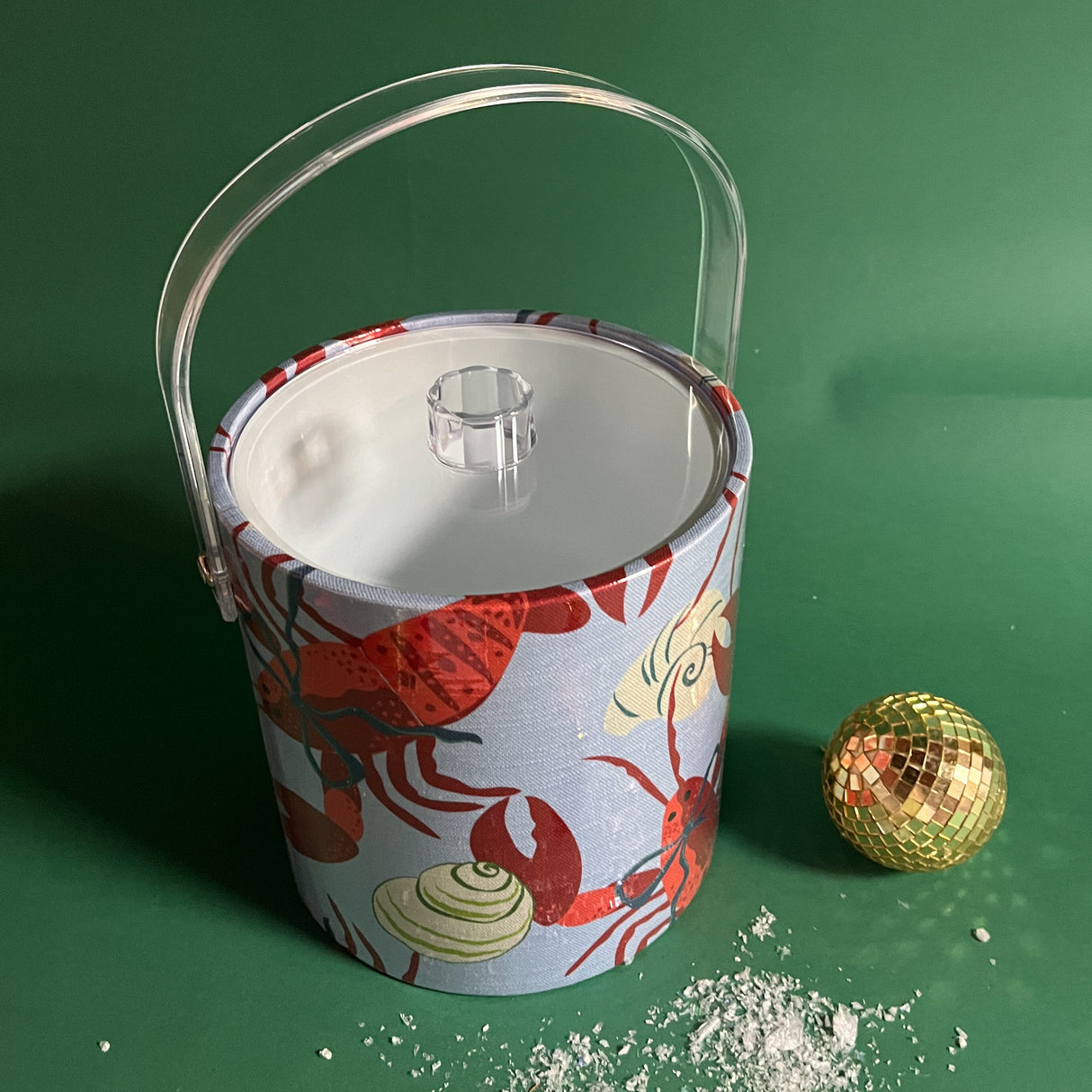 Rock Lobster blue bow is a Light blue acrylic ice bucket covered in a red lobster and shell pattern. Shown here with the handle extended and the clear lid closed on the ice bucket