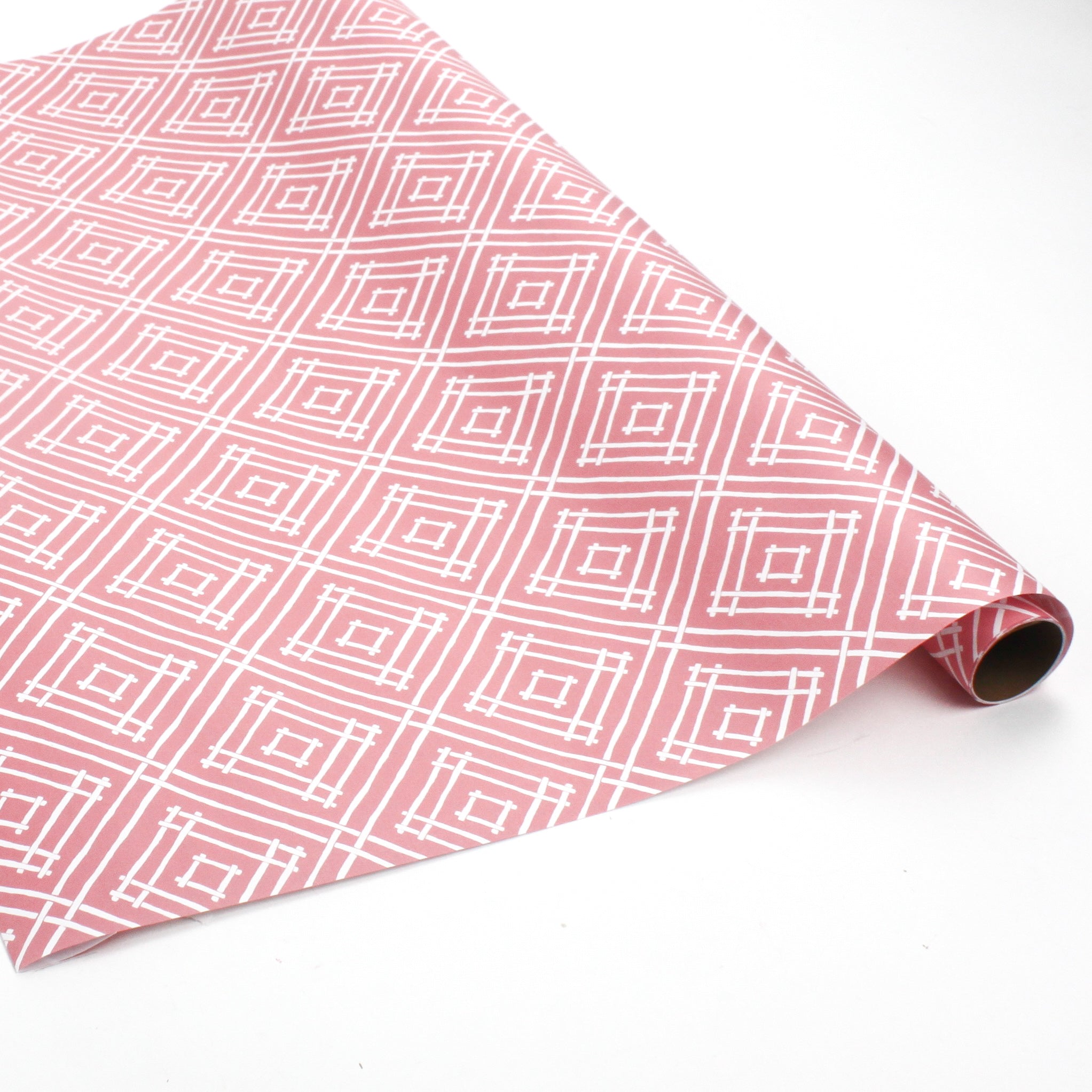 a roll of wrapping paper with a geometric lattice pattern in pink