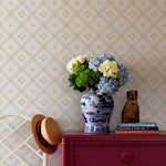 a flower filled vase against a wall of green and white wallpaper in a bamboo trellis design.