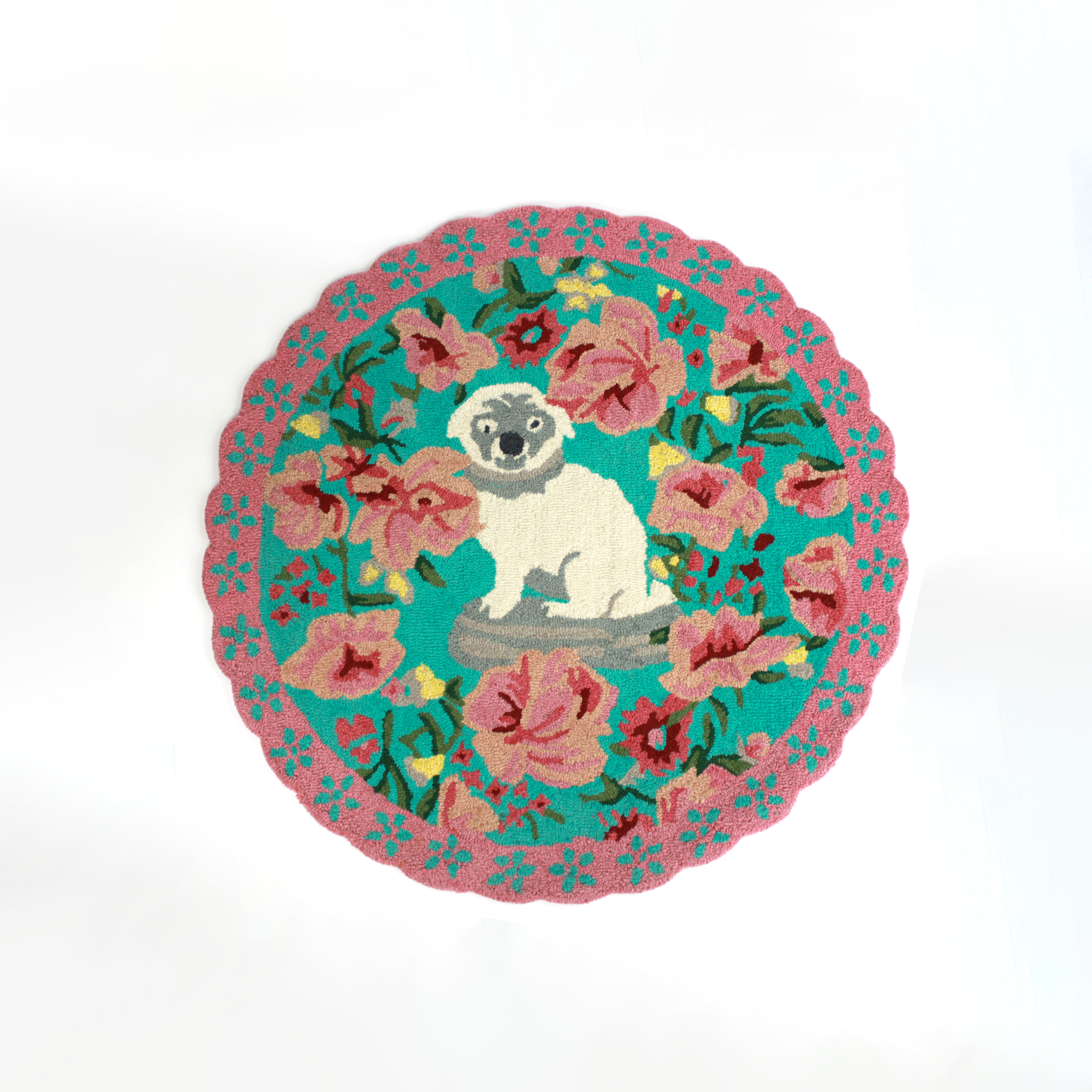 A pink and green floral rug featuring a scalloped border and large central pug motif