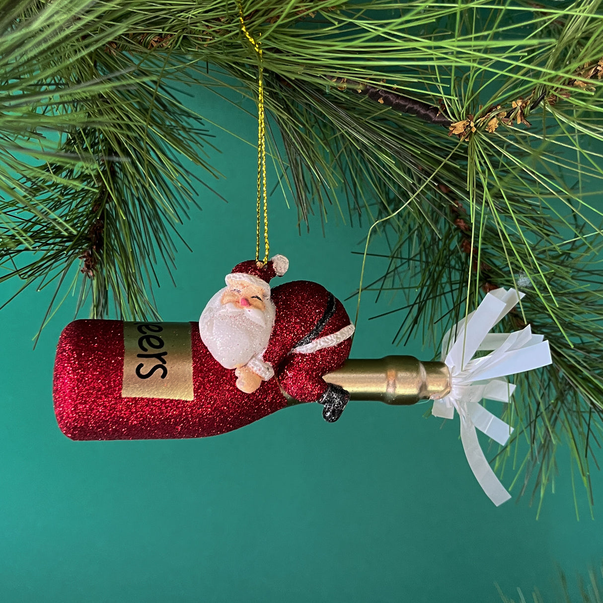 a santa riding a red champagne bottle ornament against a green background