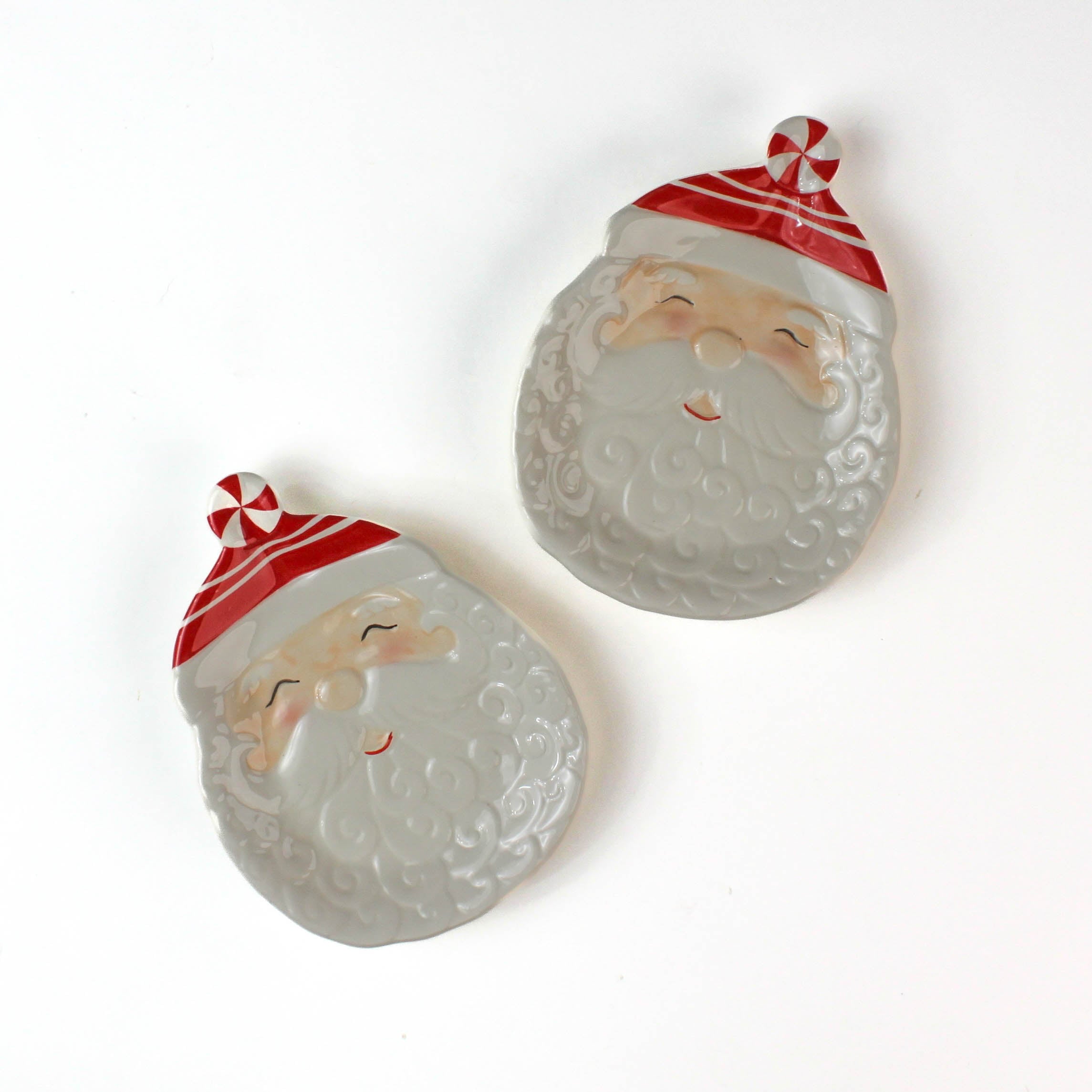 Two ceramic Santa Claus face christmas plates on a white background