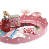 Pink christmas tray with a santa face on the bottom filled with candy and drinks on a white background