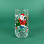 clear drinking glasses with festive Santa Claus designs, holiday on a green background