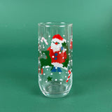 clear drinking glasses with festive Santa Claus designs, holiday on a green background