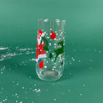 Clear holiday drinking glass with Santa, reindeer, ornaments, and falling snow design on a green background