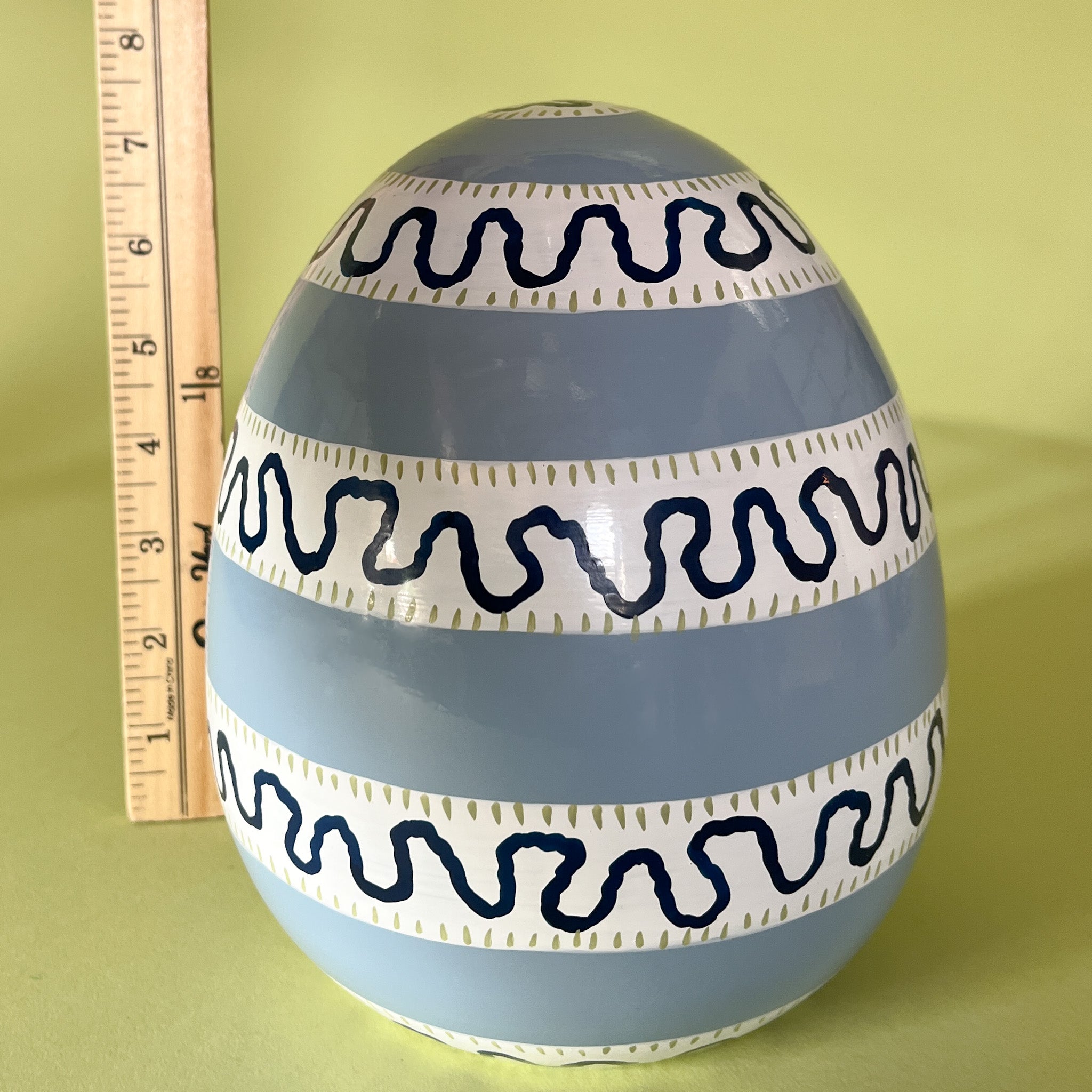 a blue striped large decorative easter eggs with a ruler behind to illustrate scale