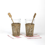 two seagrass wrapped glasses from madcap cottage each with a pineapple swizzle stick inside. 