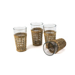 Set of four clear drinking glasses with woven rattan sleeves.
