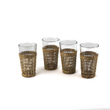 Set of four clear drinking glasses with woven rattan sleeves.