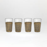 Four glasses with wicker sleeves on a white background