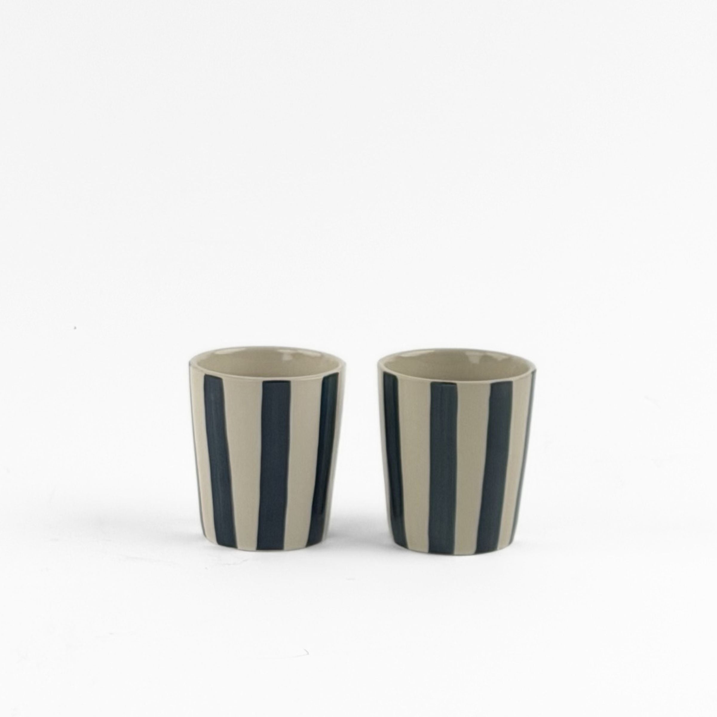 2 blue striped ceramic cups in on a white background. 