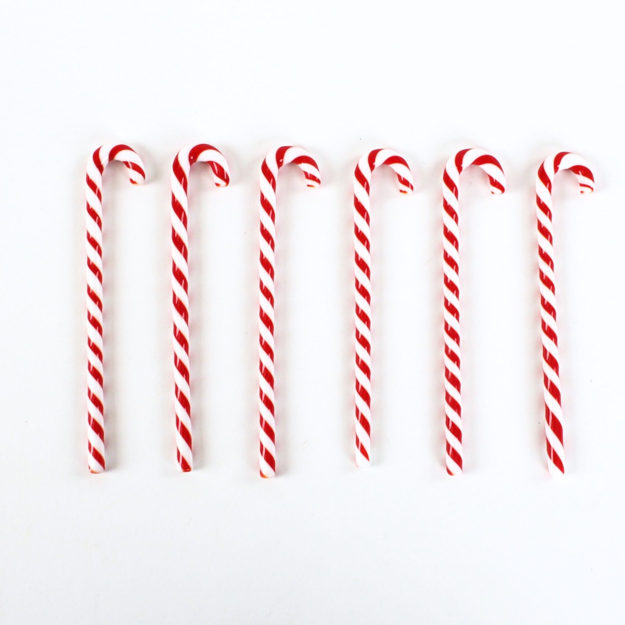 a set of 6 red and white candy cane drinks stirrers against a plain white background. 