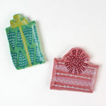 set of two christmas accent plates, one plate in the shape of a green gift, the other in the shape of a pink gift, both on a white background.