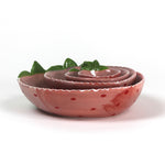 a set of four pink ceramic strawberry dishes in graduating sizes.