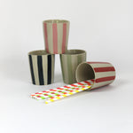 A set of four striped ceramic cups in black, green, pink and red