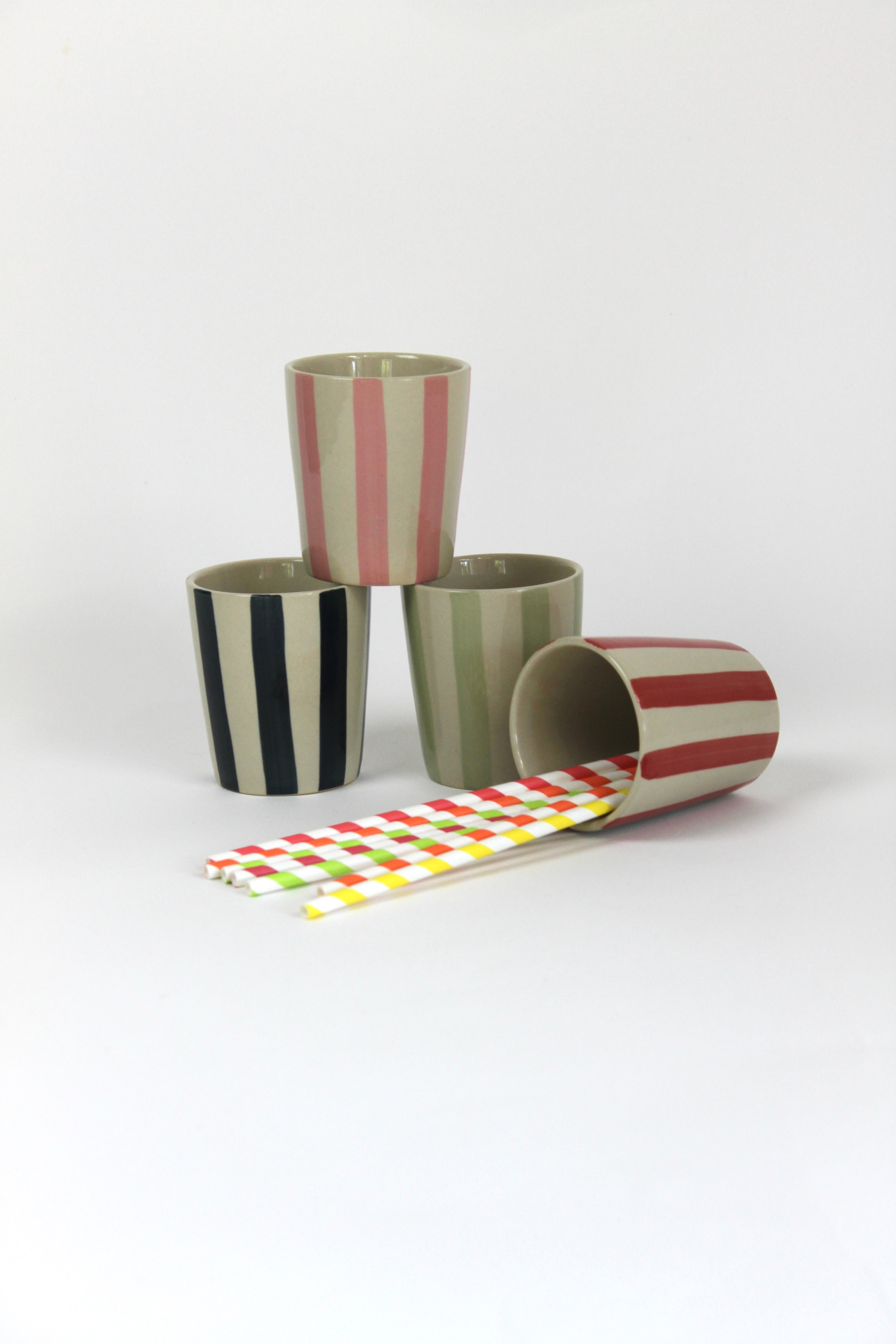 A set of four striped ceramic cups in black, green, pink and red