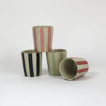 a set of four striped ceramic cups in black, pink, green and red. 