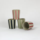 a set of four striped ceramic cups in black, pink, green and red. 